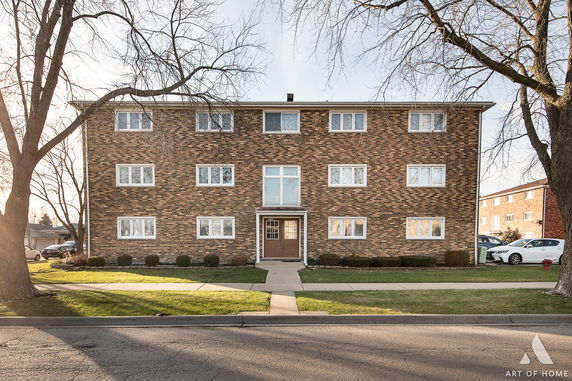 Front view of a three-story brick apartment building with multiple windows.