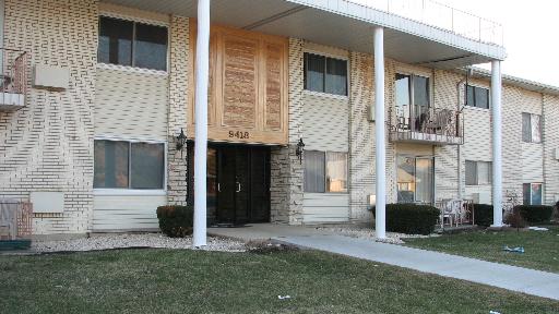 Front view of a two-story apartment building with balconies and white columns.