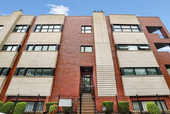 Front view of a multi-story brick building with large windows.