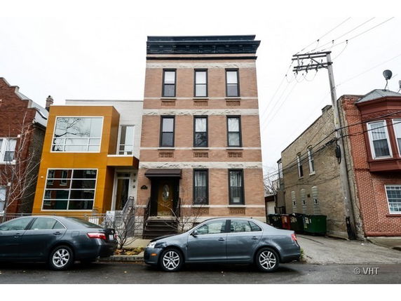 Front view of a multistory brick building with large windows and a modern design element on the left.