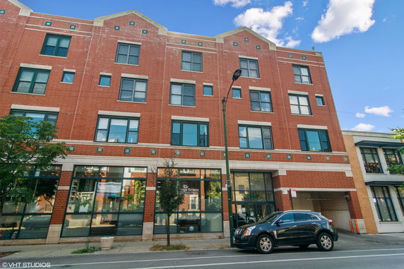 Front view of a multi-story brick building with large windows and a street view.