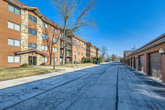 Front view of a multi-story apartment building with brick facade and attached garages.