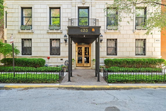Front view of a multi-story building entrance with decorative windows and a canopy.