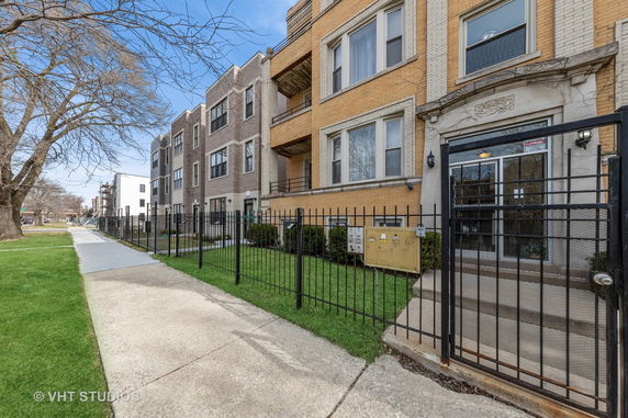 Front view of a multi-story apartment building with a gated entrance.
