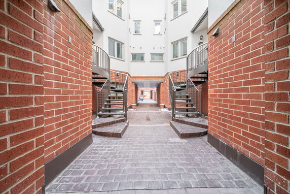 Front view of a multi-story building with a brick exterior and staircases leading to entrances.