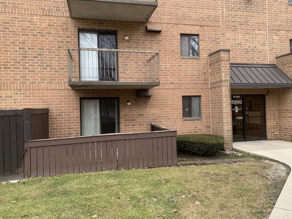 Front view of a brick multi-story building with balconies and an entrance.
