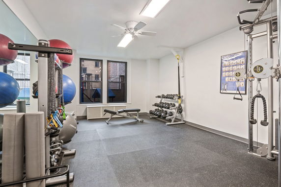 Indoor gym area with exercise equipment and weights.