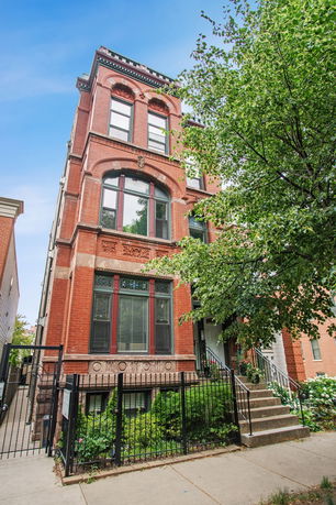 Front view of a multi-story brick building with decorative windows and a gated entrance.