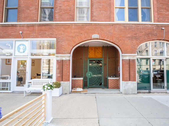 Front view of a brick building with large arched doorways and windows.
