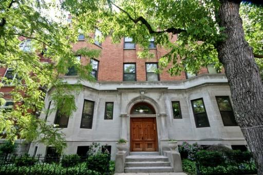 Front view of a multi-story brick building with a central entrance and decorative archway.