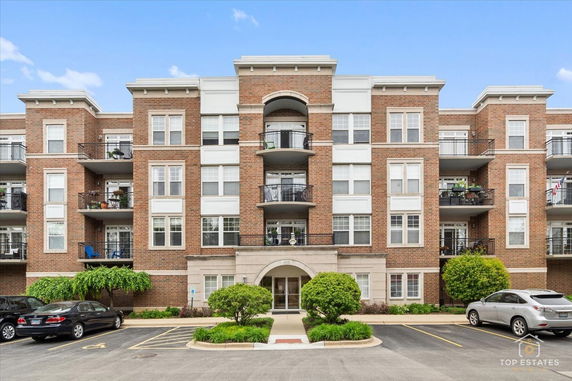 Front view of a multi-story residential building with balconies and parking area.