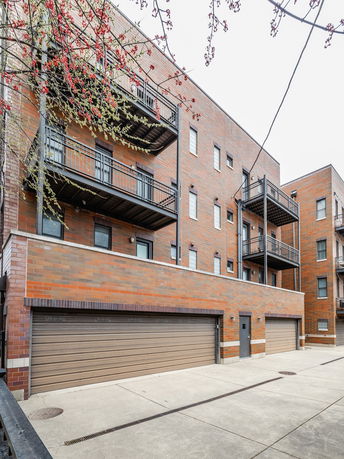 Front view of a multi-story building with balconies and garages.