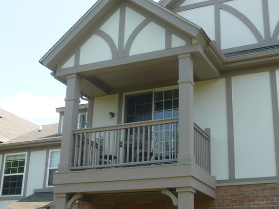 Front view of a house with a small balcony and Tudor-style architecture.