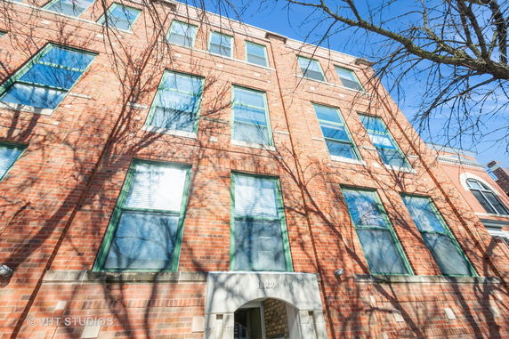 Front view of a multi-story brick building with green window frames.