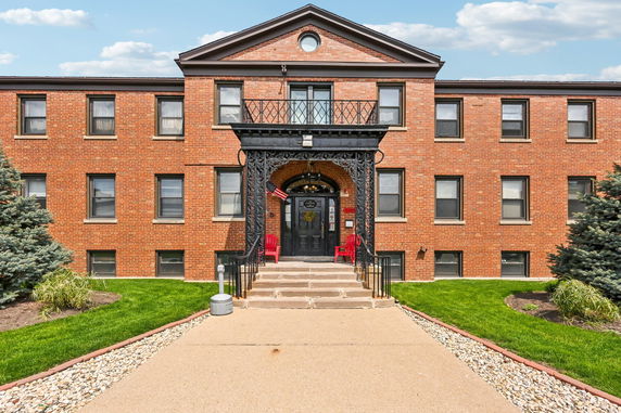 Front view of a three-story brick building with symmetrical windows and a decorative entrance.