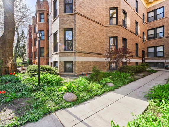 Front view of a multi-story brick apartment building with multiple windows.