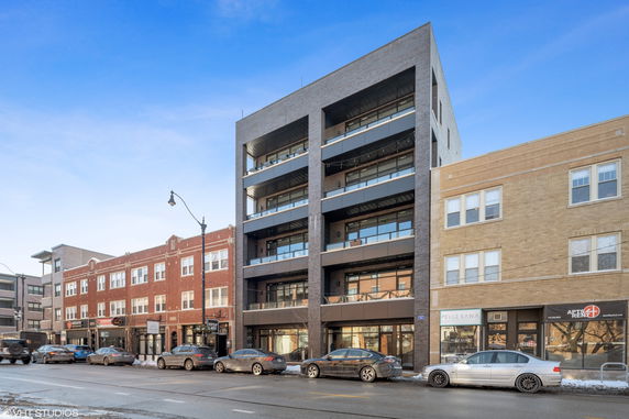 Front view of a multi-story modern building with large windows and balcony spaces.