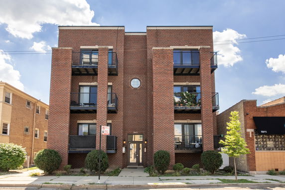 Front view of a multi-story brick apartment building with balconies.