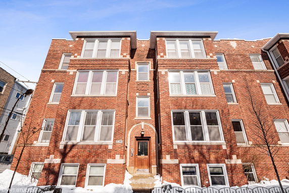 Front view of a three-story brick building with large windows.