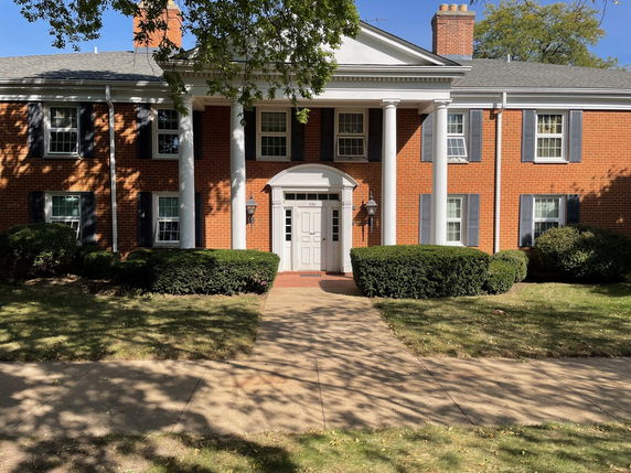 Front view of a two-story brick house with columns and white trim.
