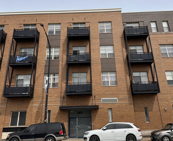 Front view of a multi-story brick apartment building with balconies.