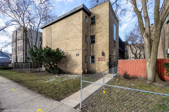 Front view of a three-story brick building with a gate.