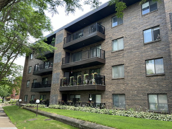 Front view of a multi-story brick apartment building with balconies.