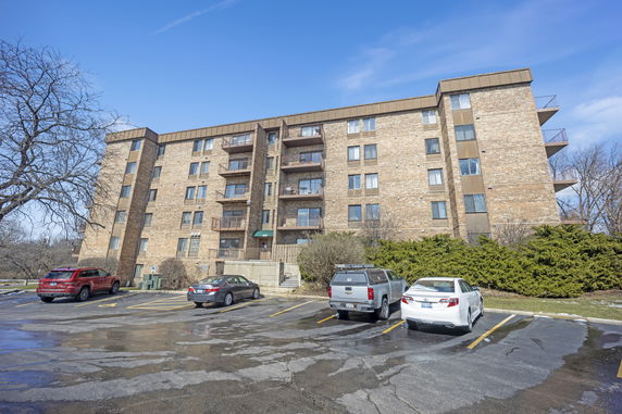 Front view of a multi-story brick apartment building with balconies.