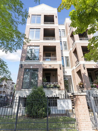 Front view of a multi-story brick apartment building with balconies.