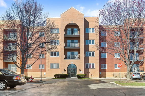Front view of a multi-story brick apartment building with balconies.