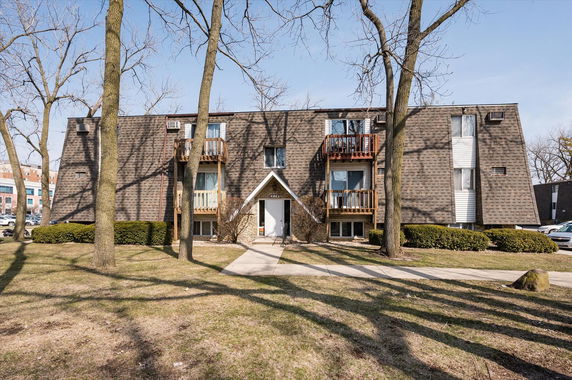 Front view of a multi-story residential building with a shingled exterior and small balconies.