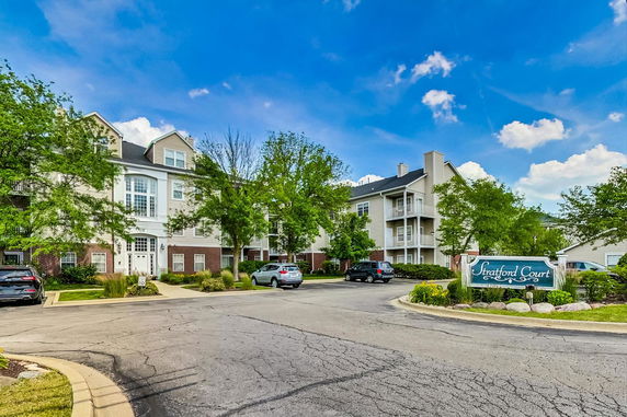 Front view of a multi-story residential building with balconies and parking area.