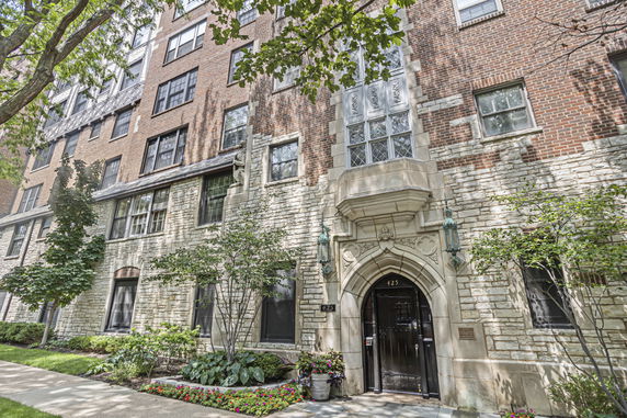 Front view of a multi-story brick building with decorative stone entryway.