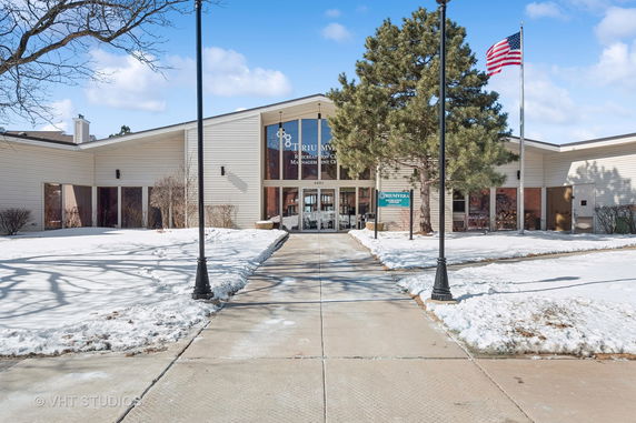 Front view of a recreational center building with large entrance windows and a pathway leading to it.