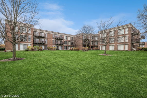 Front view of a three-story brick apartment building with multiple balconies.