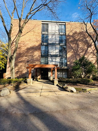 Front view of a multi-story brick building with large windows and an entrance canopy.
