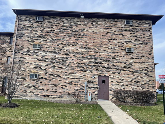 Front view of a brick multi-story building with air conditioning units.