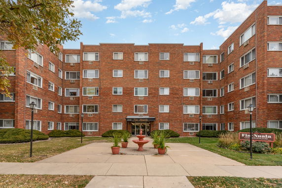 Front view of a multi-story brick condominium building with several windows.