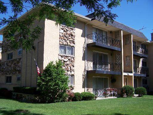 Front view of a three-story apartment building with balconies and a brick facade.