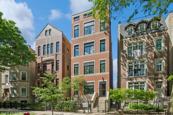 Front view of a row of multi-story brick residential buildings with large windows.