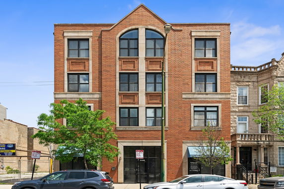 Front view of a four-story brick building with large windows.