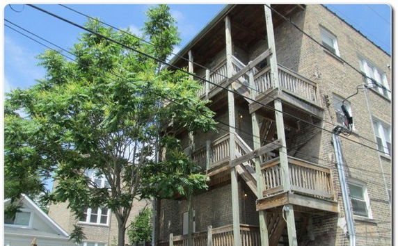 Front view of a multi-story brick building with wooden balconies.