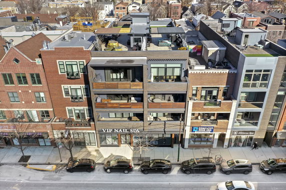 Front view of a multi-story building with balconies and commercial spaces at the ground level.