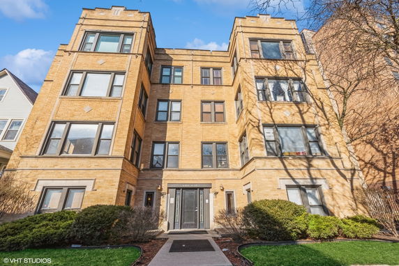 Front view of a multi-story brick apartment building with multiple windows.