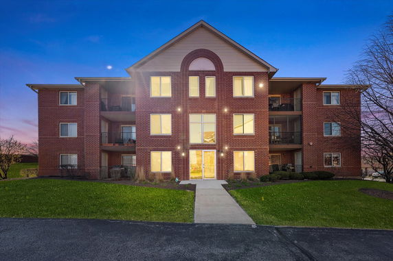 Front view of a three-story apartment building at dusk.