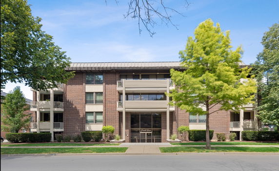 Front view of a multi-story apartment building with balconies and a central entrance.