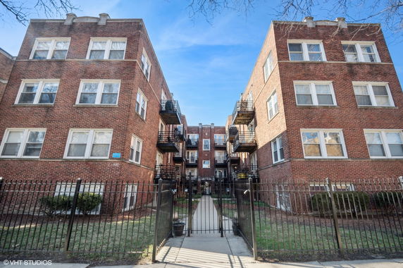 Front view of a brick apartment building with multiple levels and balconies.