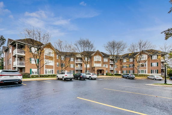 Front view of a three-story brick apartment building with multiple balconies.
