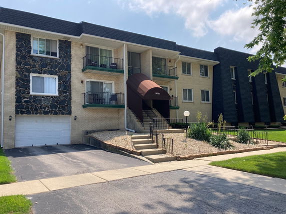 Front view of a two-story residential building with balconies and a garage.
