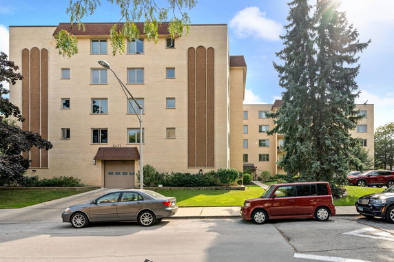 Front view of a multi-story beige brick apartment building.